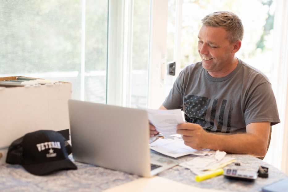 a man wearing an american flag t shirt using a laptop computer at a table