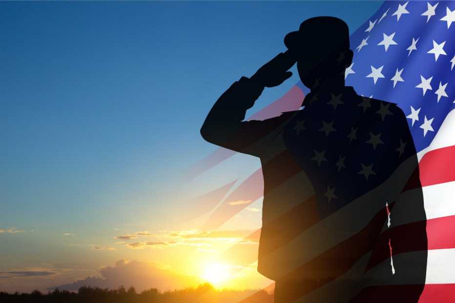 a silhouette of soldier with USA flag against the sunset