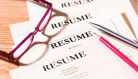a stack of resumes under a pair of glasses, a pen and a pencil a stack of resumes under a pair of glasses, a pen and a pencil