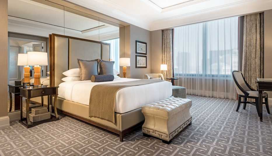 Caesars Palace offers discounts for veterans. a caesars palace hotel room with one bed, desk, side table and large window