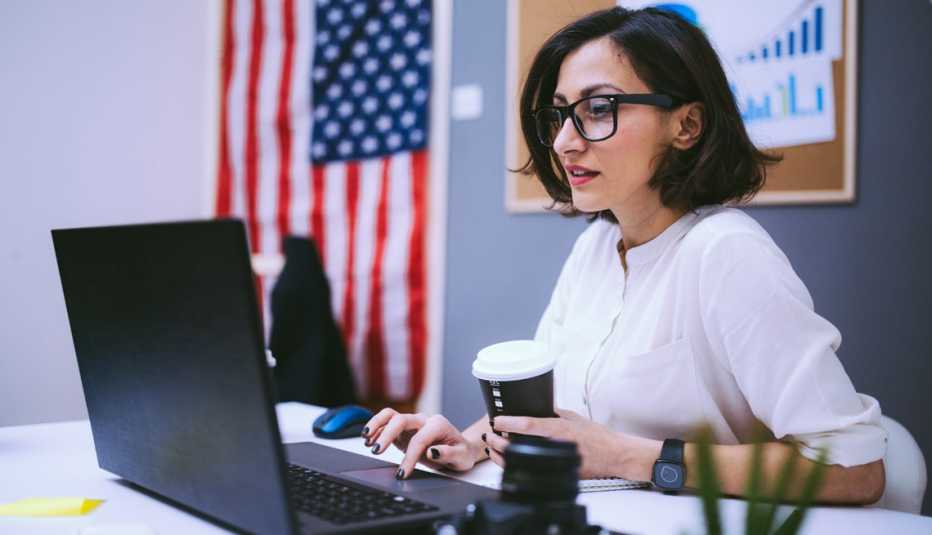 Job Search Tips for Military Spouses a woman works on a laptop. an american flag hangs in the background.