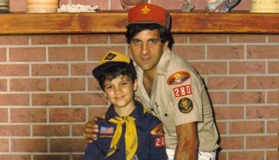 a father and son stand before a fireplace