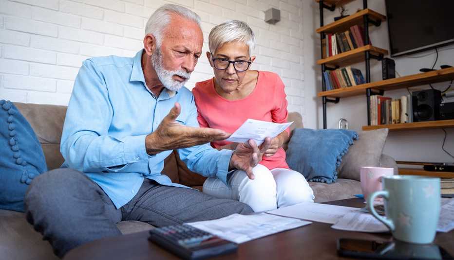 A man and a woman are sitting on the couch looking at bills A man and a woman are sitting on the couch looking at bills