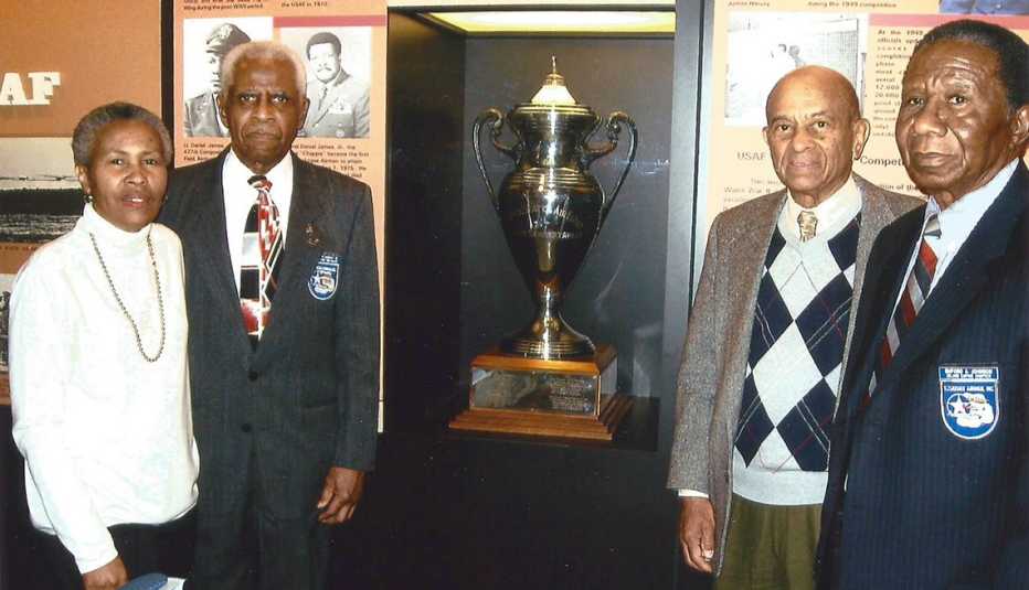 james harvey and colleagues stand in front of their top gun trophy