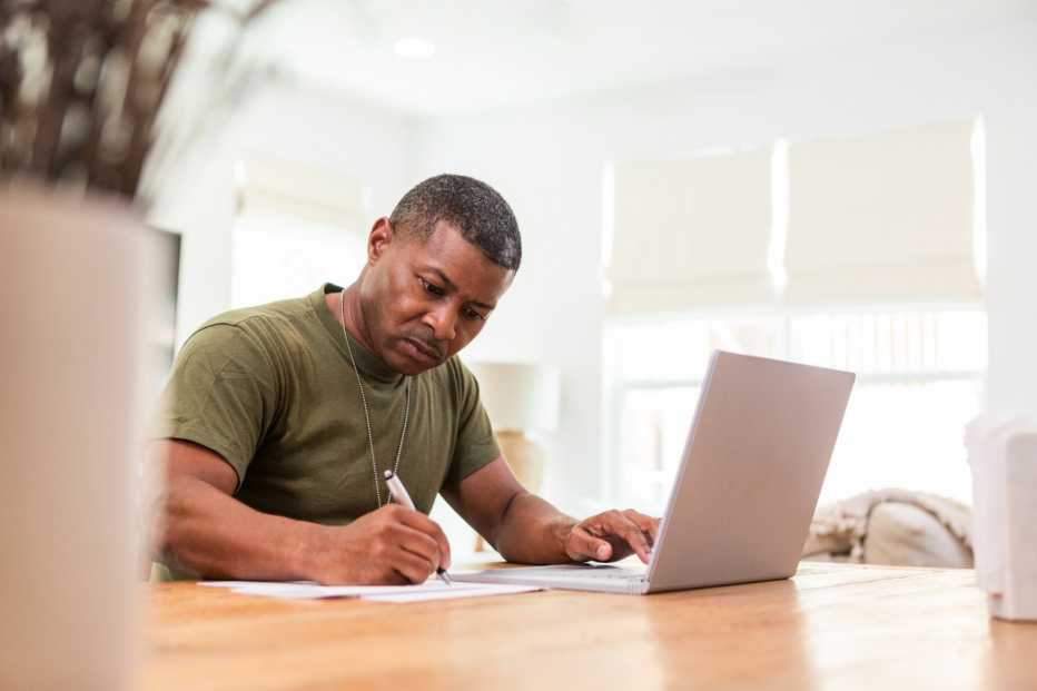 a veteran wearing military dog tags using a computer at a table