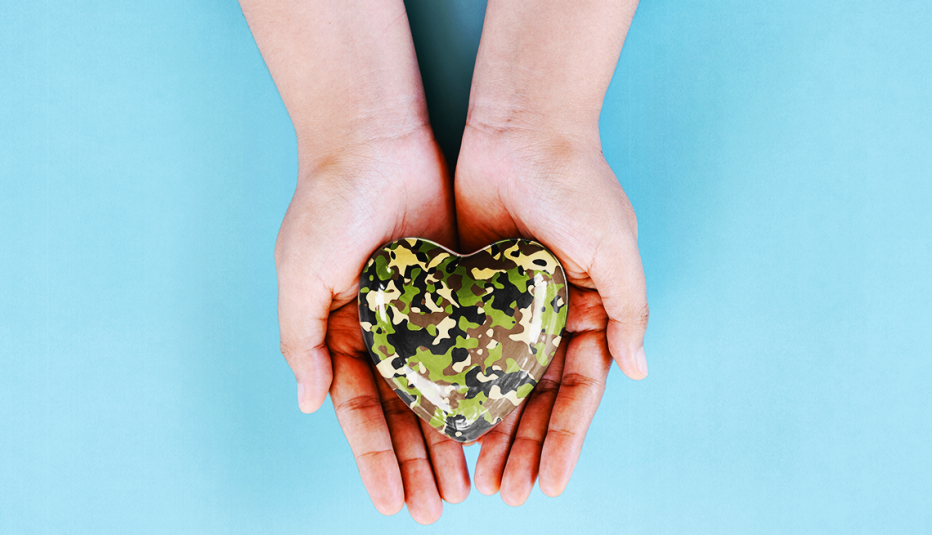 hands hold a camouflage heart