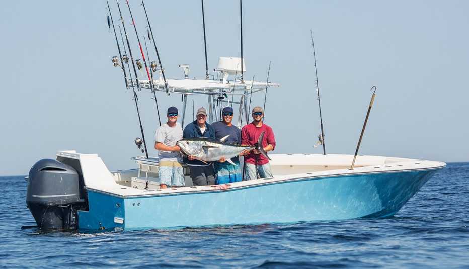 men on a boat display a fish