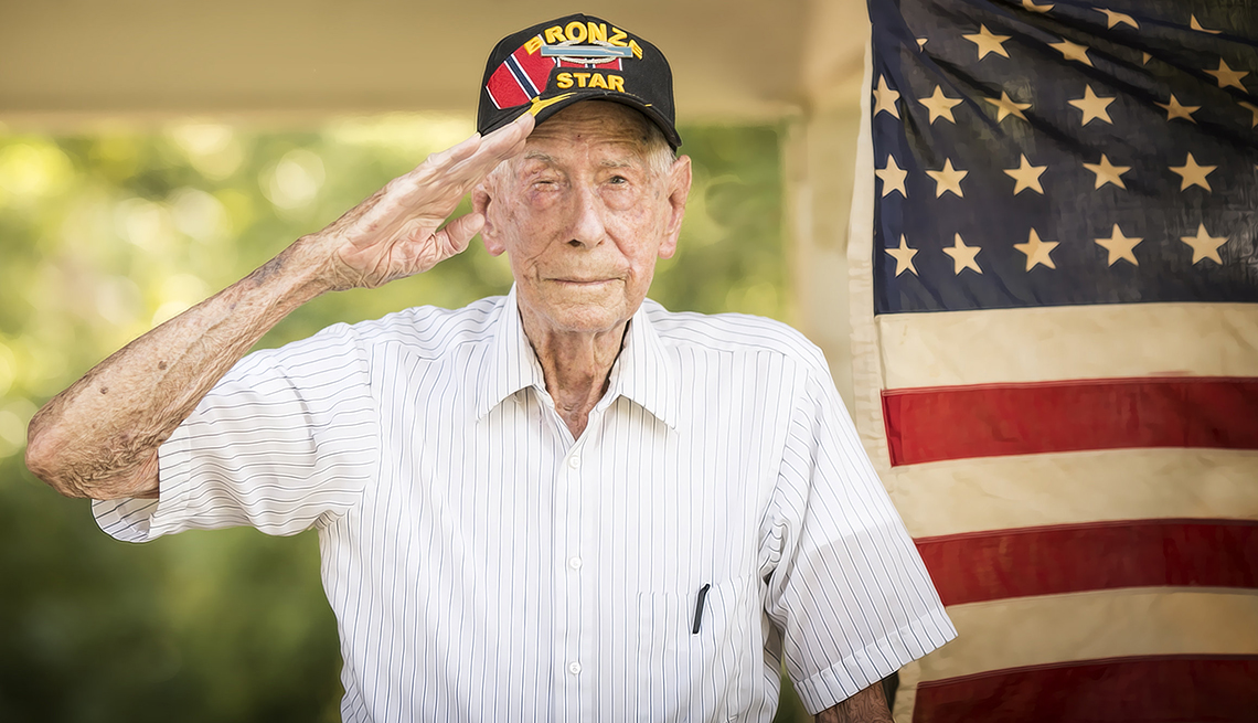 a man in a hat salutes with a flag behind him