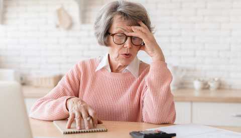 Money Mistakes to Avoid During an Economic Downturn a woman looks frustrated while looking at a calculator