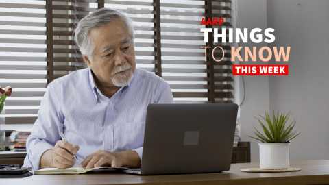 a photo shows an older adult man looking at a laptop while writing on a notepad