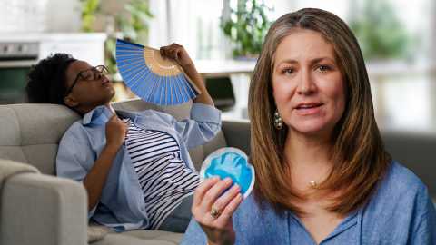 woman in blue shirt holding an ice pack while another woman in the background fans herself during a hot flash