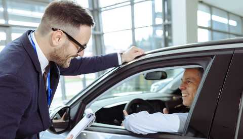 How to Save Money on Necessities When Tariffs Drive Up Prices a person in a car talking with someone outside the car