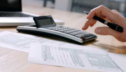 a hand is holding a pen while touching a calculator