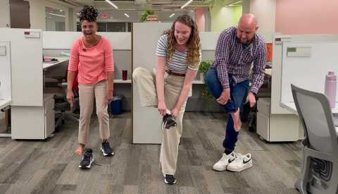 people tying their shoes while balancing on one foot in an office