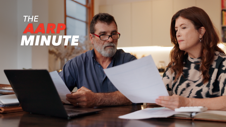 a man an woman sitting at a desk looking at paper work. The A A R P minute