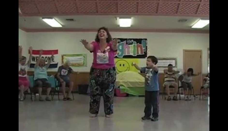 A woman standing with a child with her arms up in the air, smiling