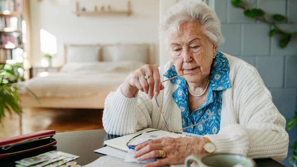 A woman sitting at a table holding glasses, looking at papers