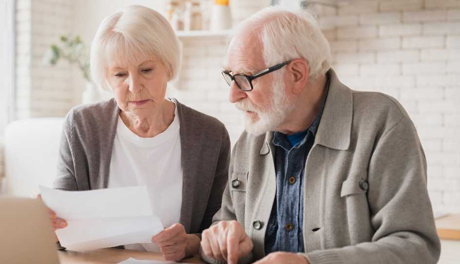 Two older adults look over a piece of paper