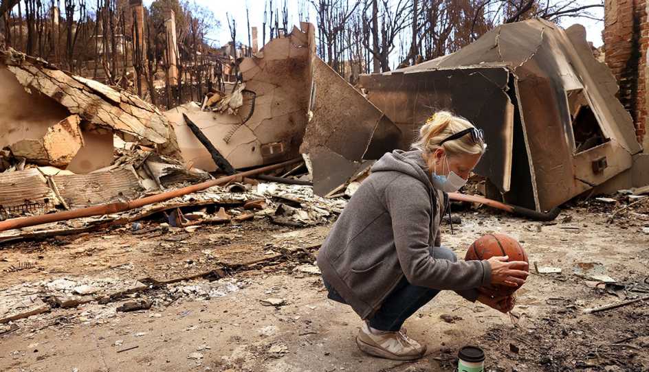 a woman is going through what is left of her home after the wildfires