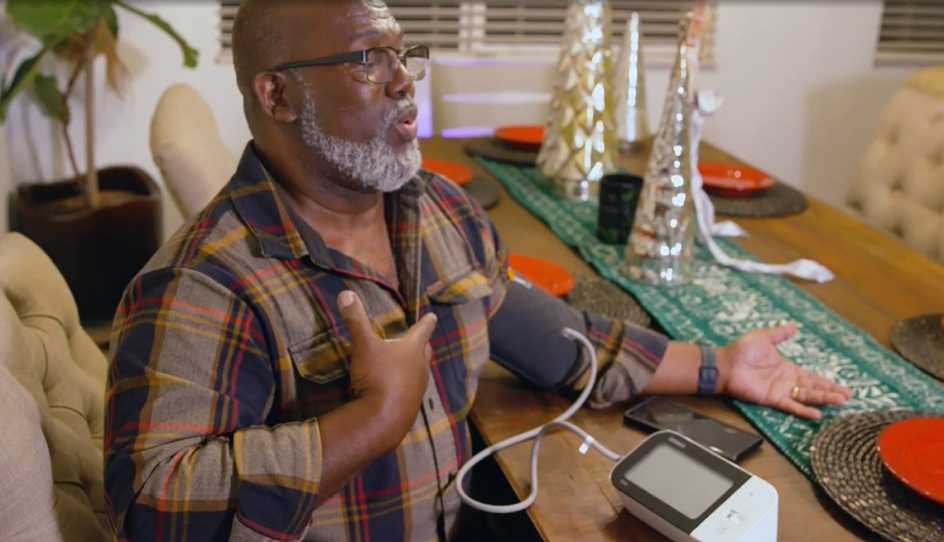 Older African American man taking his blood pressure at home using a modern device.