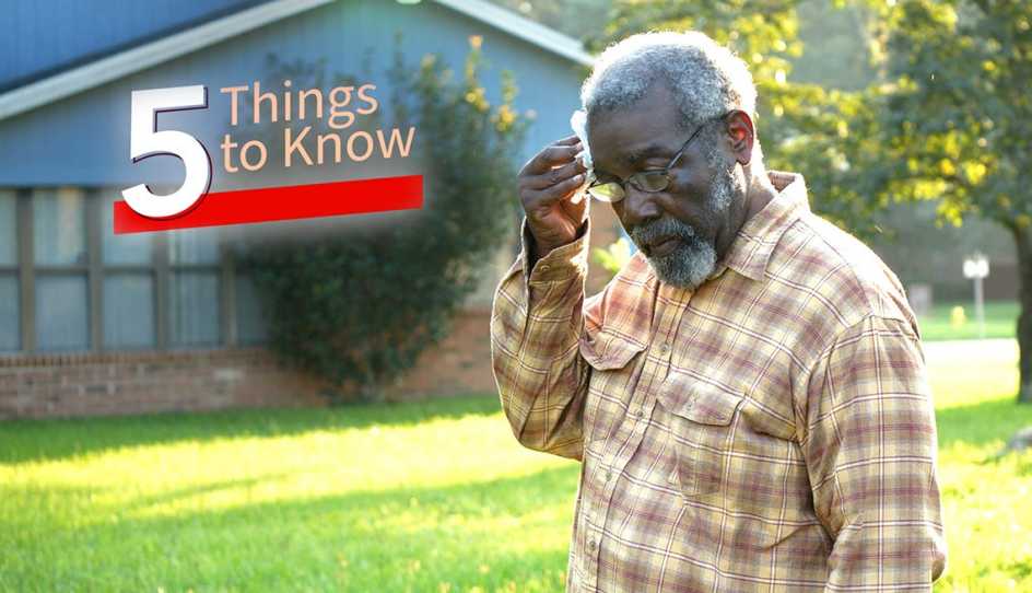 A man wiping his forehead with paper due to the heat outside