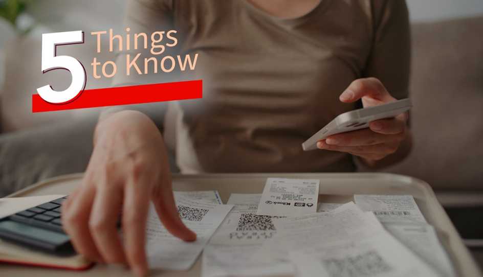 a person flipping through receipts while using a calculator
