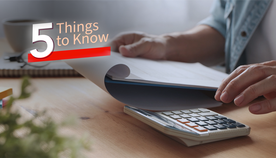 a hand typing on a calculator while holding a notepad in the other hand