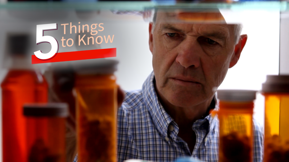 man looking at medication bottles