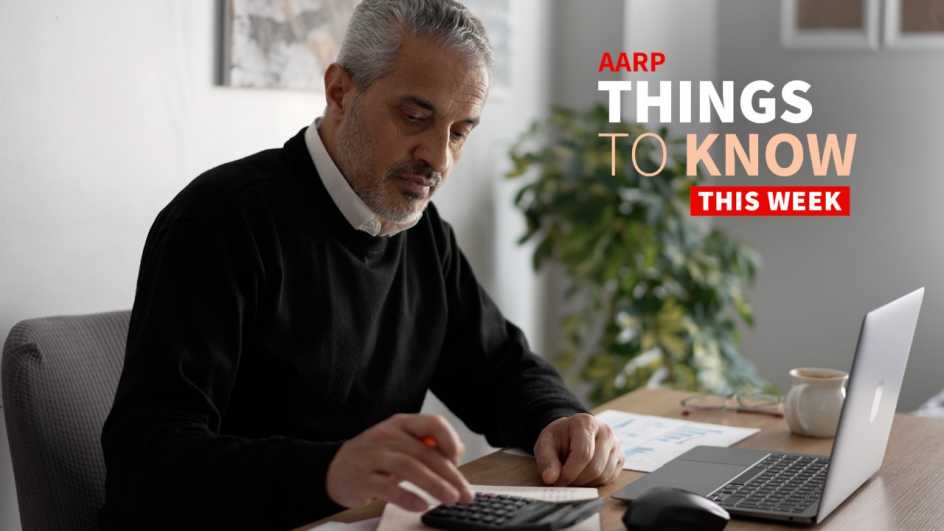 a photo shows a man sitting at a desk working with a calculator and a laptop