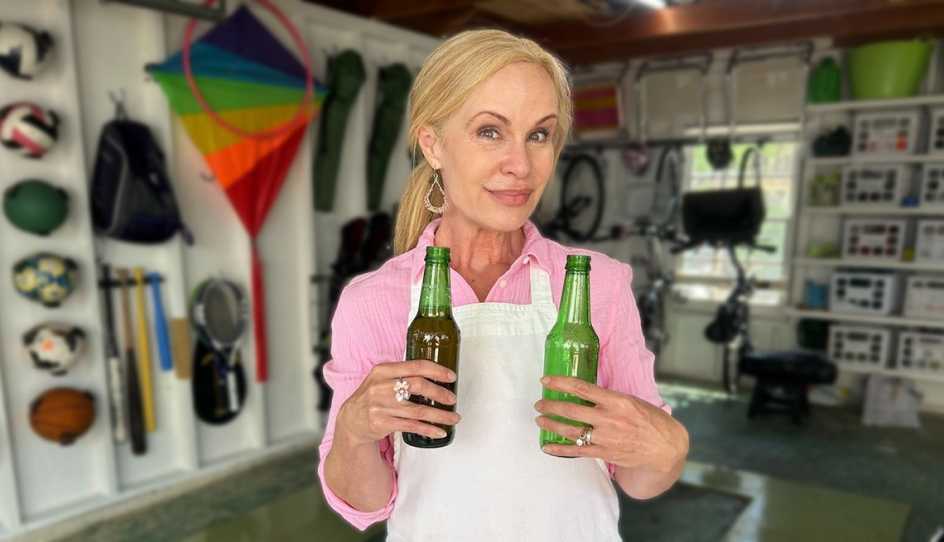 a woman is holding two beer bottles