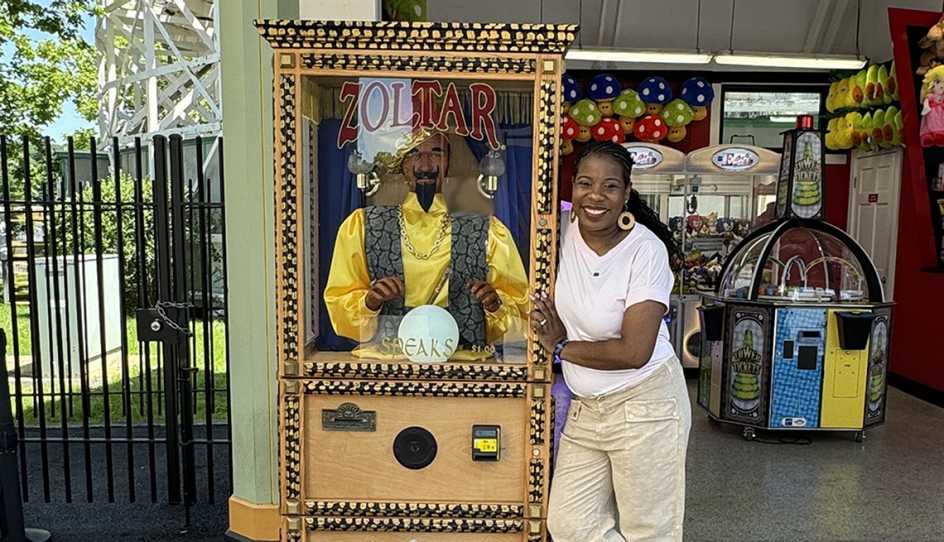 a woman stand next to a machine zoltar
