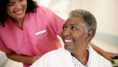 female patient in a wheel chair looking up at her nurse