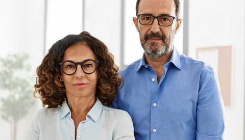 a female worker in a light blue shirt and a male worker in a darker blue shirt frown