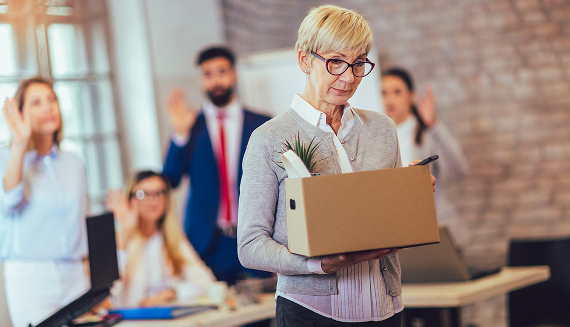 older woman leaving office with a box of belongings