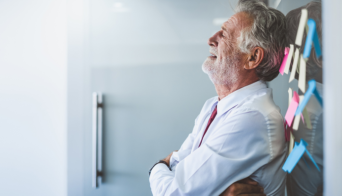 An older man leaning against a wall