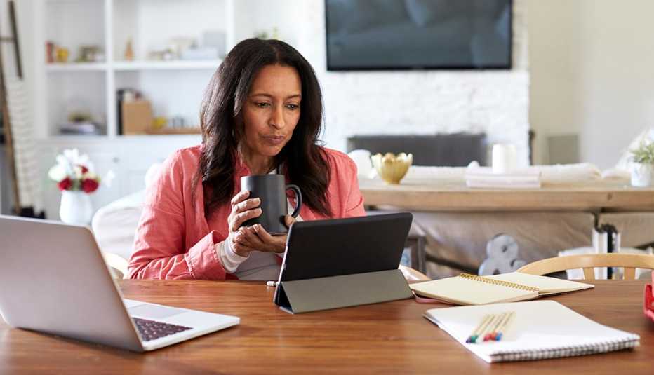A woman sits at a table in her house while she works from home