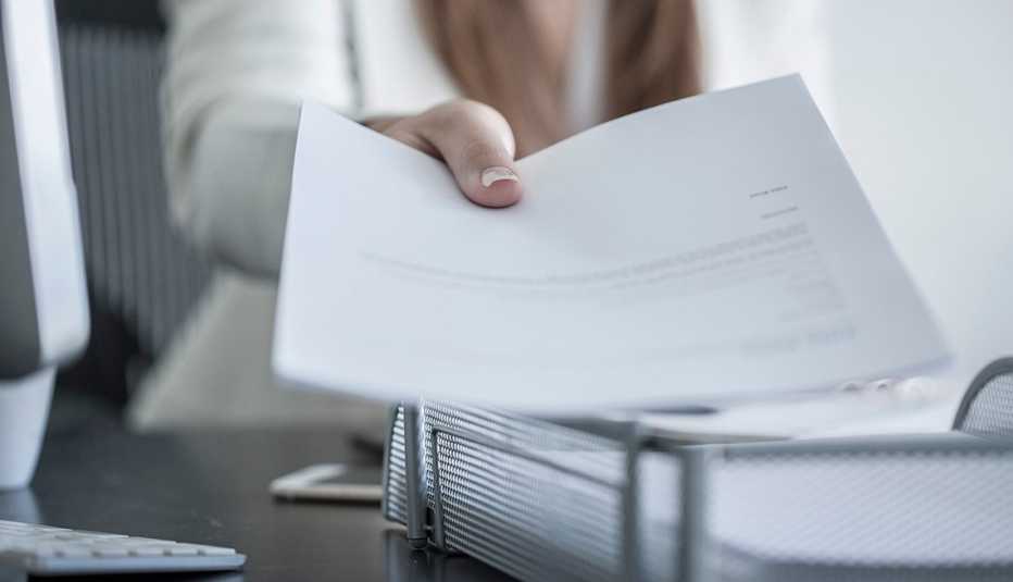 a woman's hand putting a document in a bin