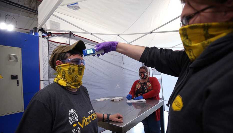 A worker gets a temperature check before being allowed back at work