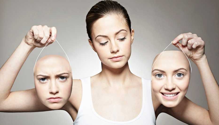 A woman holds two masks of her face with happy and sad expressions A woman holds two masks of her face with happy and sad expressions