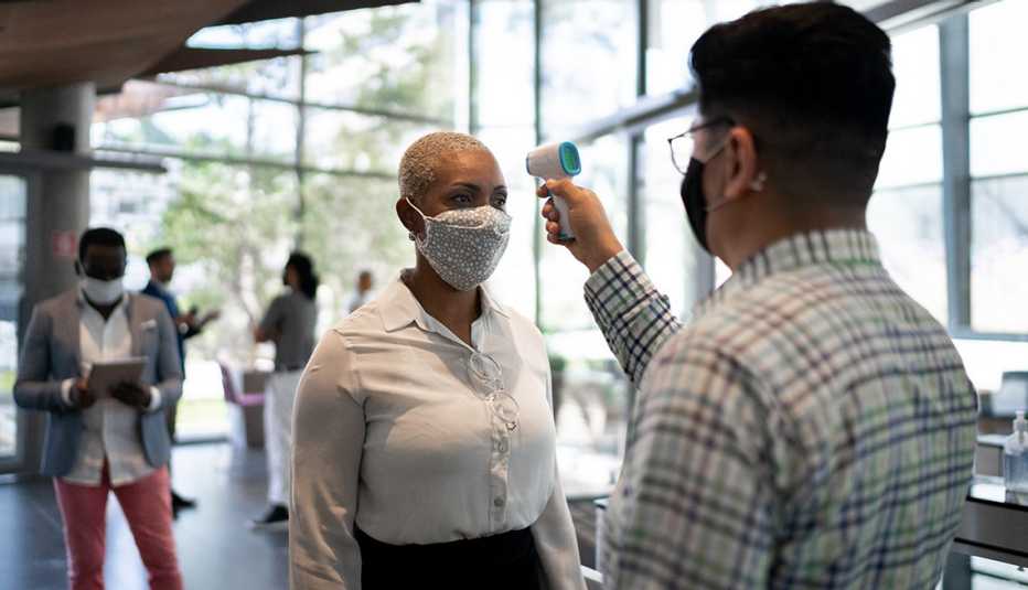 A woman is getting her temperature checked at the office