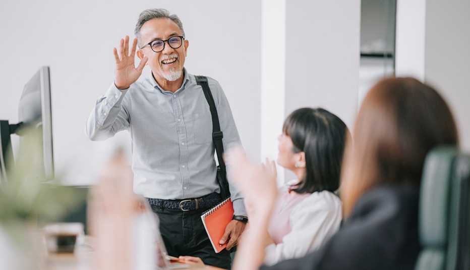 A man waves to people while walking into an office