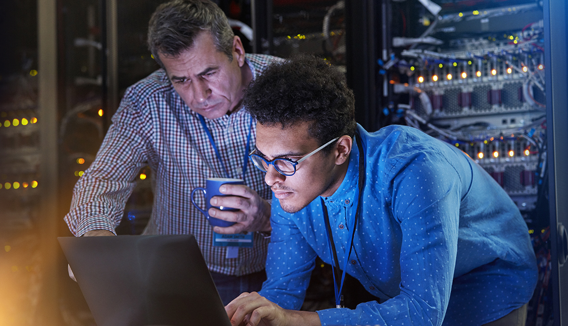an older man and younger man look at a computer