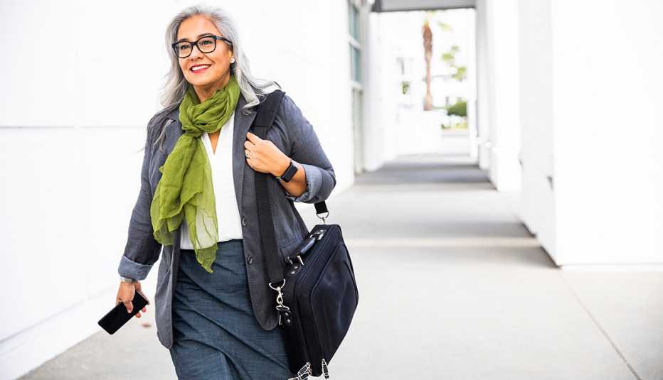 a woman is walking down a hall with a computer bag
