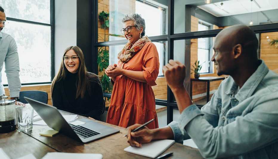 cheerful co-workers smile at one another during a meeting in an office setting