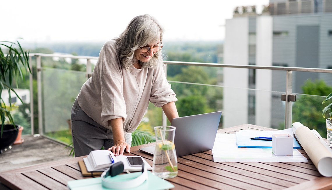 A woman standing at her desk outside on a balcony