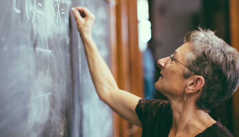 A woman teacher writes on a chalkboard