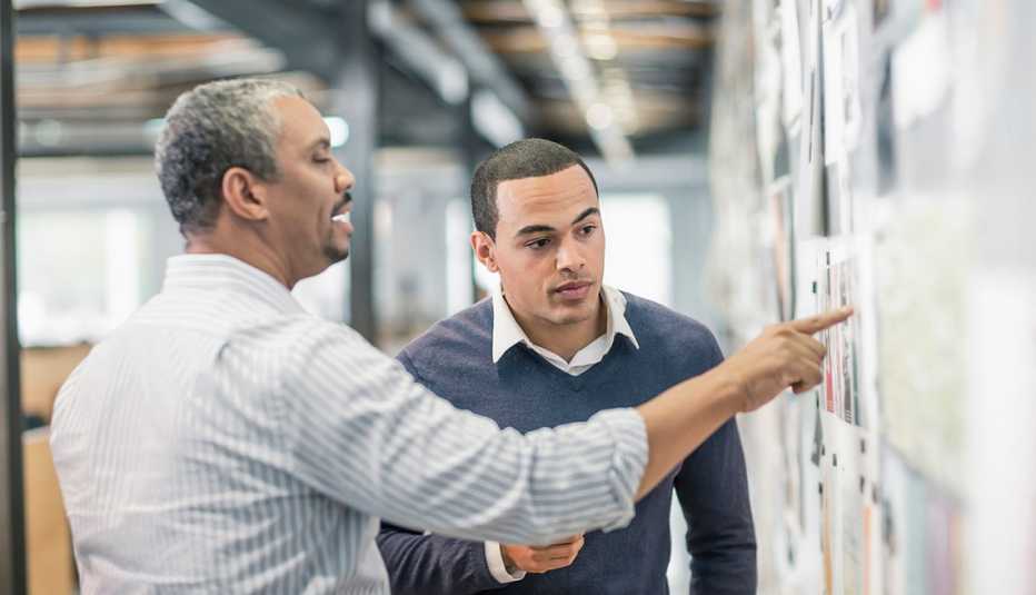 Two Men looking at Photographs on a Bulletin Board, Changing Careers