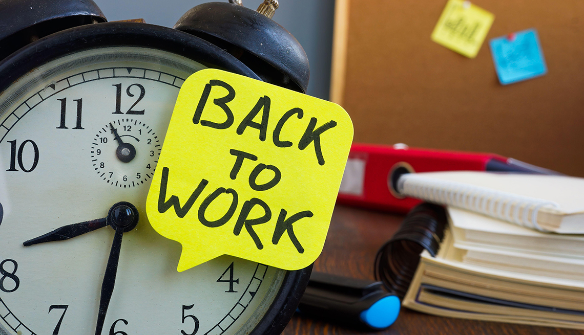 an alarm clock with a yellow sheet of paper with the words back to work on it