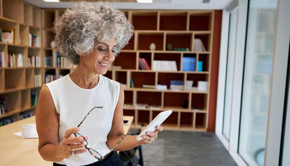 A woman is looking at her phone in an office
