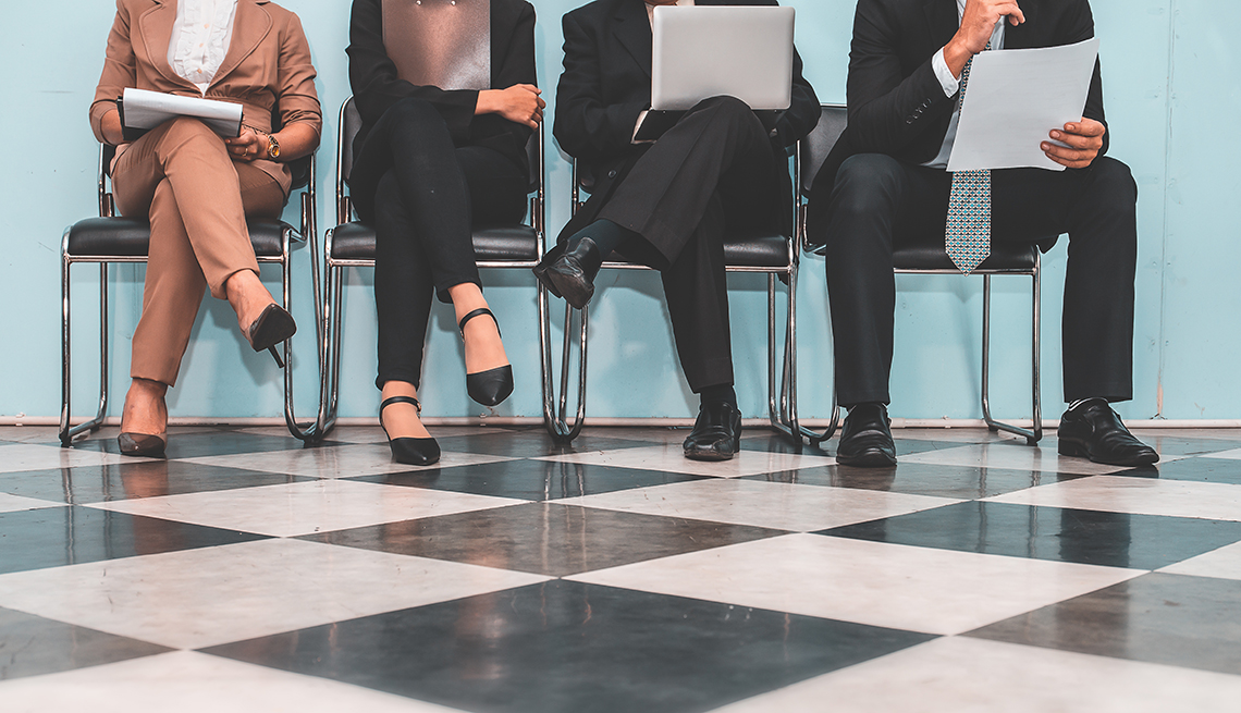 a line of men and women wait for a job interview